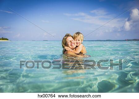 Picture - Enthusiastic mother hugging son in tropical ocean. Fotosearch