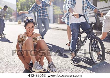 Enthusiastic teenage girl skateboarding with friends on sunny urban street View Large Photo Image Stock Image - Enthusiastic teenage girl skateboarding with friends on sunny urban street. Fotosearch