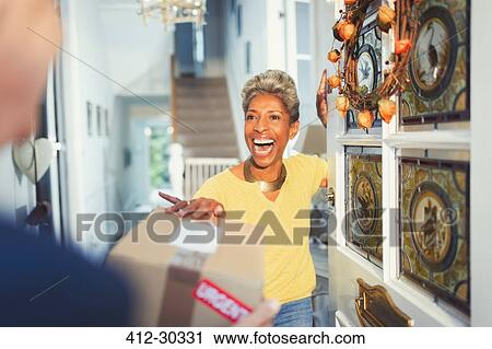 Enthusiastic woman receiving package delivery at front door View Large Photo Image Stock Image - Enthusiastic woman receiving package delivery at front door. Fotosearch