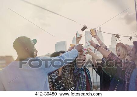 Enthusiastic young adult friends toasting cocktails at rooftop party View Large Photo Image Stock Image - Enthusiastic young adult friends toasting cocktails at rooftop party. Fotosearch