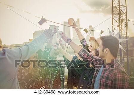 Enthusiastic young adults toasting cocktails at rooftop party View Large Photo Image Stock Photo - Enthusiastic young adults toasting cocktails at rooftop party. Fotosearch