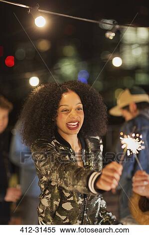 Enthusiastic young woman waving sparkler at rooftop party View Large Photo Image Stock Photography - Enthusiastic young woman waving sparkler at rooftop party. Fotosearch