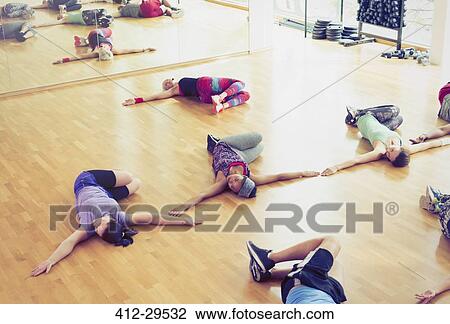 Stock Image - Exercise class doing twisted stretch in studio. Fotosearch