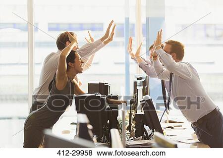 Exuberant business people high-fiving over computers in office View Large Photo Image Stock Photo - Exuberant business people high-fiving over computers in office. Fotosearch