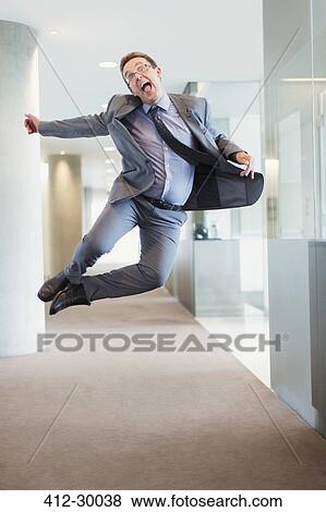 Exuberant businessman jumping for joy in office corridor View Large Photo Image Stock Photo - Exuberant businessman jumping for joy in office corridor. Fotosearch