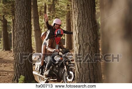 Exuberant young woman riding motorcycle in woods View Large Photo Image Stock Image - Exuberant young woman riding motorcycle in woods. Fotosearch