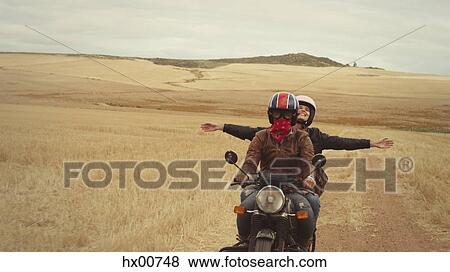 Exuberant young woman riding motorcycle in rural countryside View Large Photo Image Stock Photo - Exuberant young woman riding motorcycle in rural countryside. Fotosearch