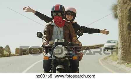 Exuberant young woman riding motorcycle on sunny road View Large Photo Image Stock Photo - Exuberant young woman riding motorcycle on sunny road. Fotosearch