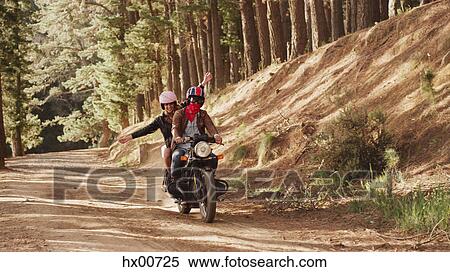 Exuberant young woman riding motorcycle on dirt road in woods View Large Photo Image Stock Photography - Exuberant young woman riding motorcycle on dirt road in woods. Fotosearch