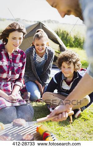Family barbecuing at sunny campsite View Large Photo Image Stock Image - Family barbecuing at sunny campsite. Fotosearch