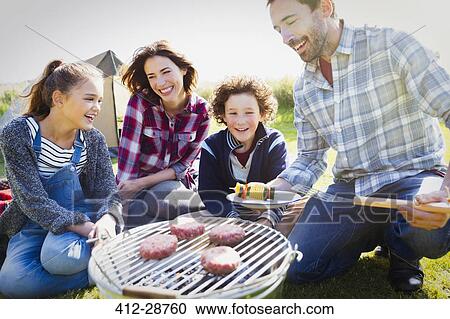 Stock Image - Family barbecuing at sunny campsite. Fotosearch