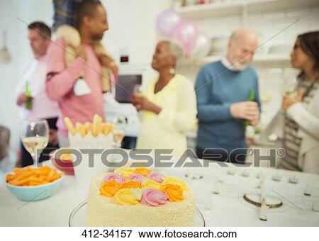 Stock Photo - Family enjoying party behind cake. Fotosearch