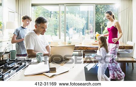 Stock Photo - Family in kitchen at breakfast. Fotosearch