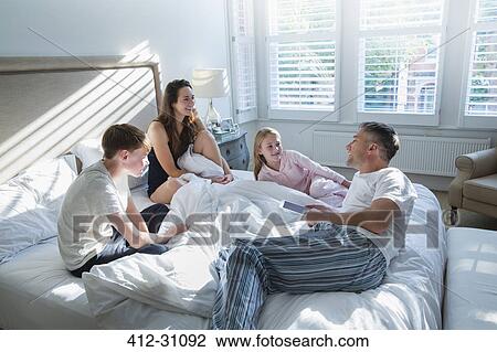 Family in pajamas relaxing on bed View Large Photo Image Stock Image - Family in pajamas relaxing on bed. Fotosearch