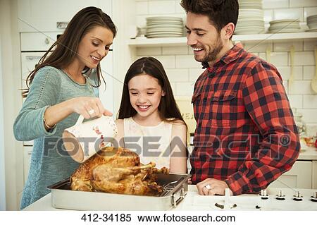 Stock Photography - Family preparing Christmas dinner turkey in kitchen. Fotosearch