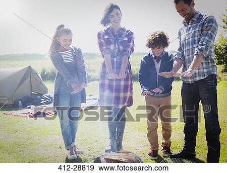 Stock Photo - Family warming hands at campfire. Fotosearch