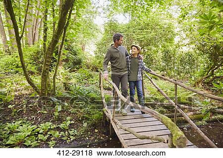 Father and son crossing footbridge in forest View Large Photo Image Stock Photo - Father and son crossing footbridge in forest. Fotosearch