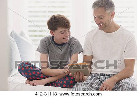 Father and son in pajamas using digital tablet View Large Photo Image Stock Photo - Father and son in pajamas using digital tablet. Fotosearch
