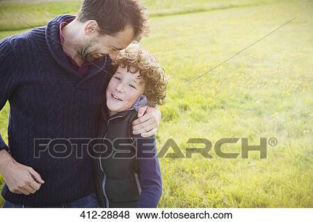 Stock Photo - Father hugging son in field. Fotosearch