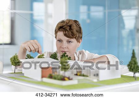 Female architect arranging building model in office View Large Photo Image Stock Image - Female architect arranging building model in office. Fotosearch