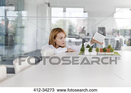 Female architect arranging model in conference room View Large Photo Image Stock Image - Female architect arranging model in conference room. Fotosearch