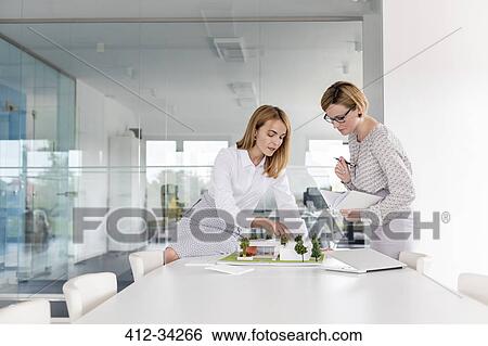 Stock Photograph - Female architects discussing model in conference room meeting. Fotosearch