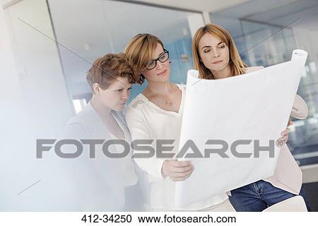 Female architects reviewing blueprints in office View Large Photo Image Stock Image - Female architects reviewing blueprints in office. Fotosearch