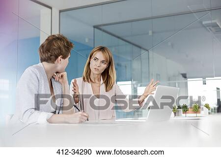 Stock Image - Female architects talking at laptop in conference room meeting. Fotosearch