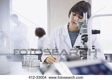 Picture - Female college student conducting scientific experiment in science laboratory classroom. Fotosearch