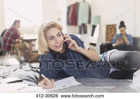 Stock Photo - Female college student studying on bed. Fotosearch