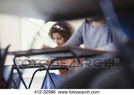 Female college student taking test at desk in classroom View Large Photo Image Stock Photograph - Female college student taking test at desk in classroom. Fotosearch