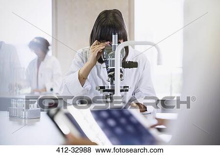 Stock Photo - Female college student using microscope in science laboratory classroom. Fotosearch