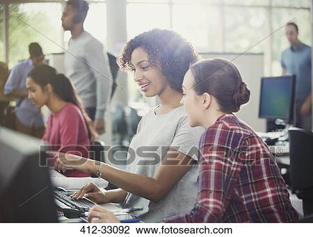 Stock Image - Female college students using computer at computer lab library. Fotosearch