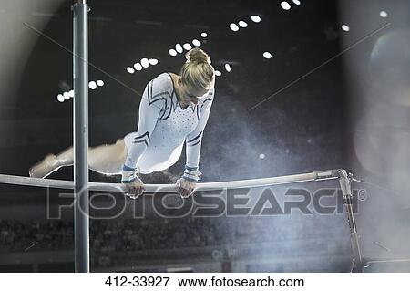 Female gymnast performing on uneven bars in arena View Large Photo Image Stock Photo - Female gymnast performing on uneven bars in arena. Fotosearch