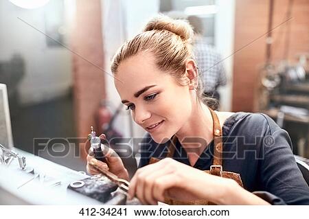 Stock Image - Female jeweler using equipment in workshop. Fotosearch