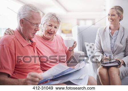 Stock Photo - Financial advisor discussing paperwork with senior couple. Fotosearch