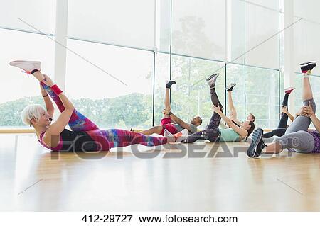 Stock Photo - Fitness instructor guiding exercise class stretching legs. Fotosearch