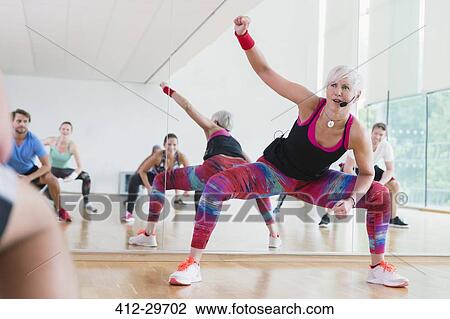 Stock Image - Fitness instructor leading aerobics class. Fotosearch