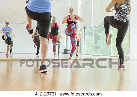 Stock Image - Fitness instructor leading aerobics class. Fotosearch
