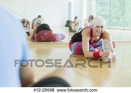 Stock Photo - Fitness instructor leading class stretching leg. Fotosearch