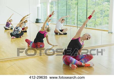 Stock Photography - Fitness instructor leading class stretching arms. Fotosearch