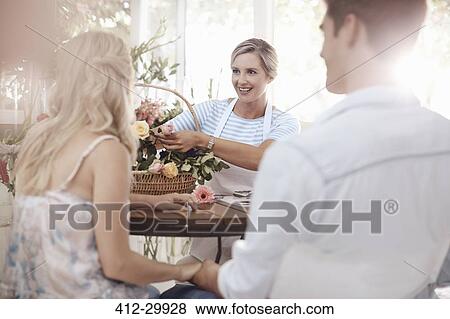 Florist discussing flowers with couple in flower shop View Large Photo Image Stock Photo - Florist discussing flowers with couple in flower shop. Fotosearch
