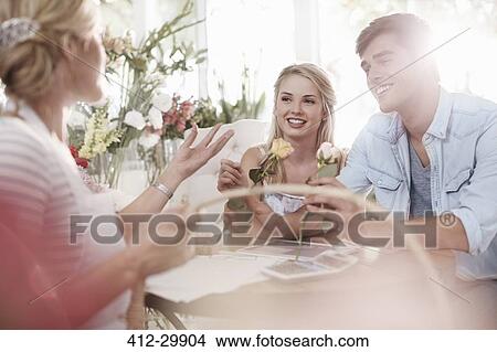 Florist discussing roses with couple in flower shop View Large Photo Image Picture - Florist discussing roses with couple in flower shop. Fotosearch
