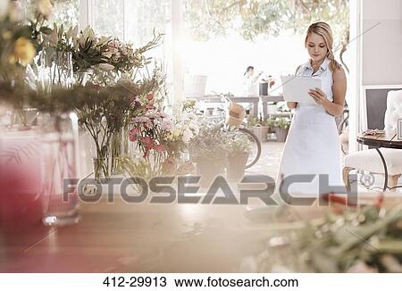 Stock Image - Florist doing paperwork in flower shop. Fotosearch