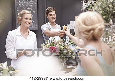 Florist giving woman rose in flower shop View Large Photo Image Stock Photo - Florist giving woman rose in flower shop. Fotosearch