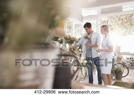 Stock Photograph - Florist helping man choosing flowers in flower shop. Fotosearch
