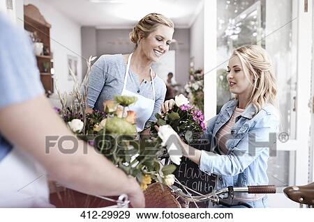 Stock Photo - Florist helping woman pick out flowers in flower shop. Fotosearch