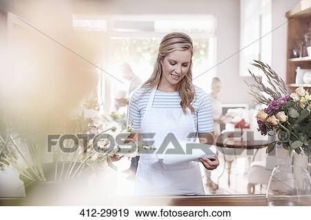 Florist reviewing paperwork in flower shop View Large Photo Image Stock Photo - Florist reviewing paperwork in flower shop. Fotosearch