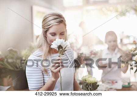 Stock Photography - Florist smelling white flower in flower shop. Fotosearch