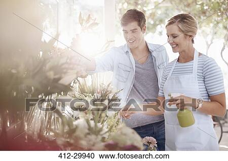 Florist spraying flowers with water bottle in flower shop View Large Photo Image Stock Image - Florist spraying flowers with water bottle in flower shop. Fotosearch